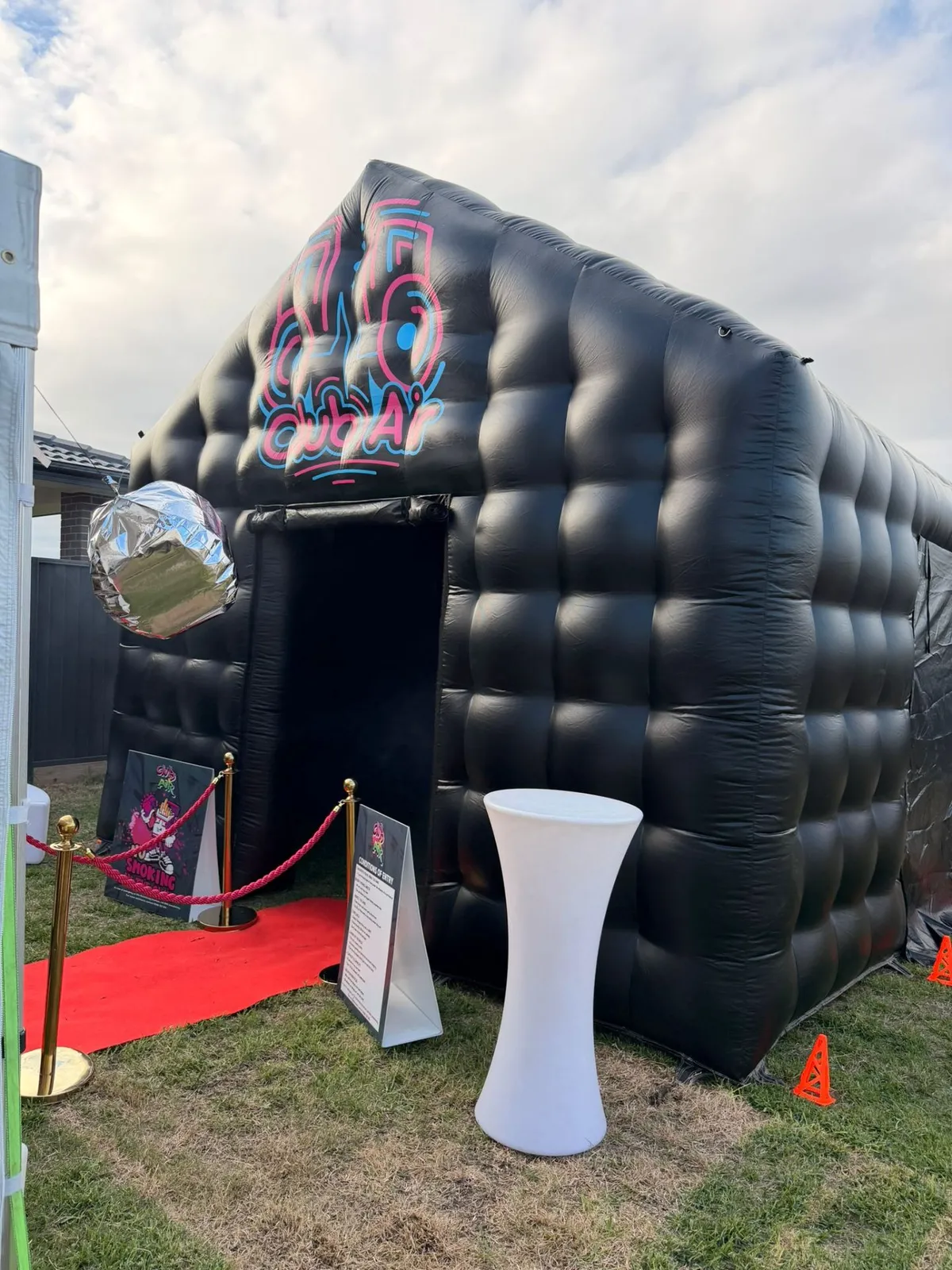 Side angle of the Club Air inflatable nightclub with a hanging disco ball and white cocktail table, Sydney